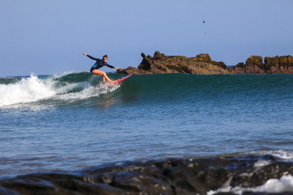 A surf girl enjoying a longboard day during winter swell season in Punta Farallon, El Ñuro spot. Surfing Peru offers a wide variety of surf spots and surfers of all levels can find perfect waves.
