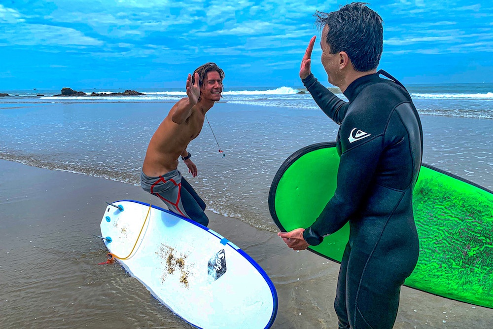 Surf Instructor and student giving high 5 after s surf lesson in Peru