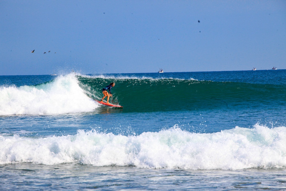 Women dropping a big wave with a longboard in Peru